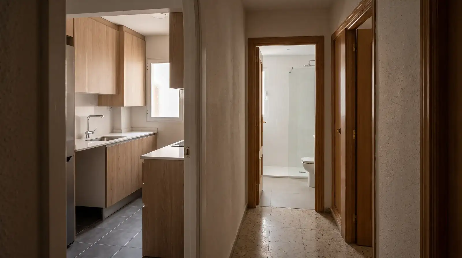 Cocina y baño reformados en un piso madrileño con muebles de madera clara, encimera blanca y alicatado claro