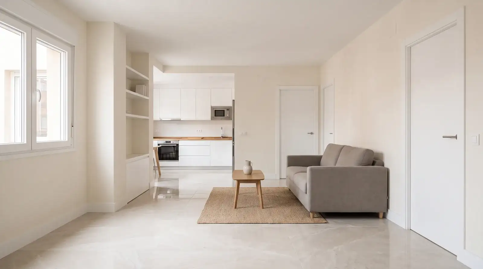 Salón reformado con suelo de porcelánico claro y cocina abierta al fondo en un piso de Madrid